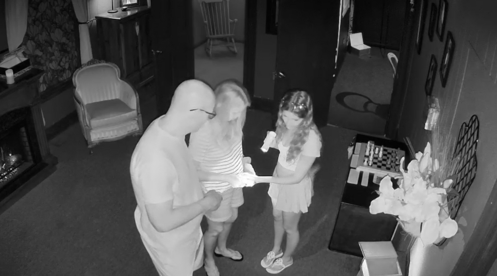 a group of three people looking at a puzzle inside Crabtree Manor- Death & Greed escape room. photo is in night vision.